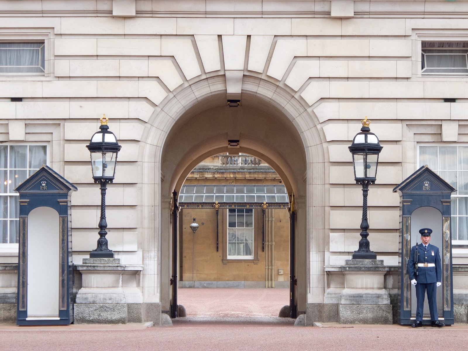A guardsman on duty beside his sentry box at an arch of Buckingham Palace.