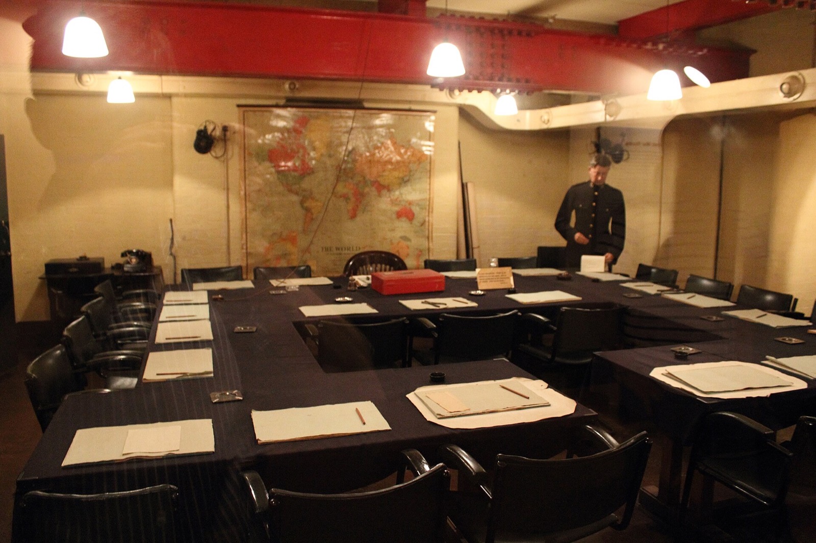The Cabinet War Room: tables set in a square under red girders, with maps on the wall.