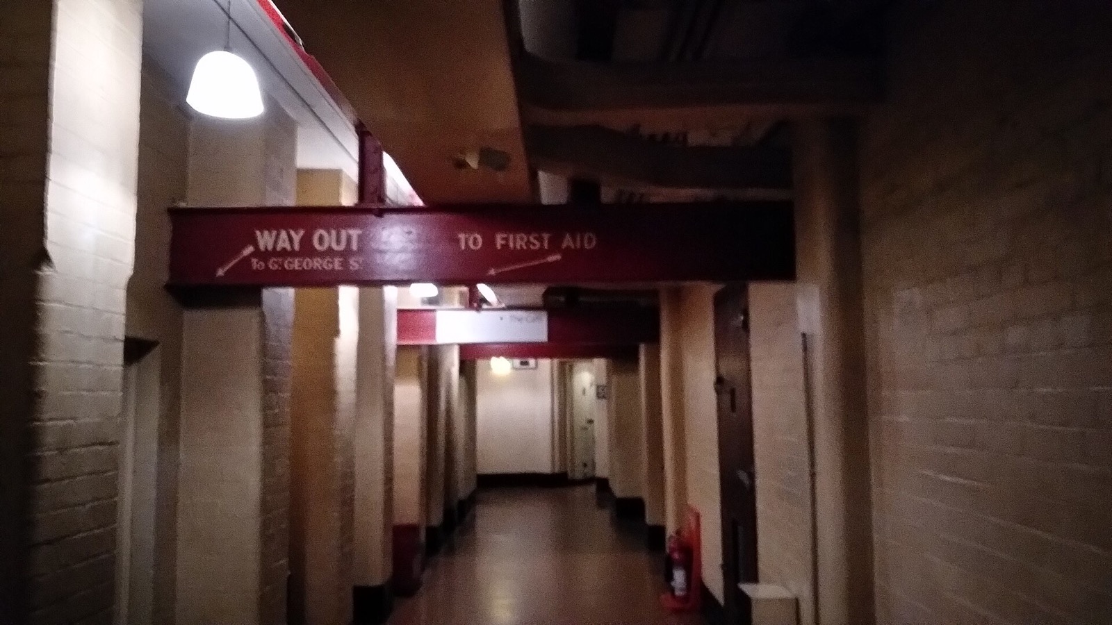 A low corridor of the Churchill War Rooms, with pipes and signs along its walls.