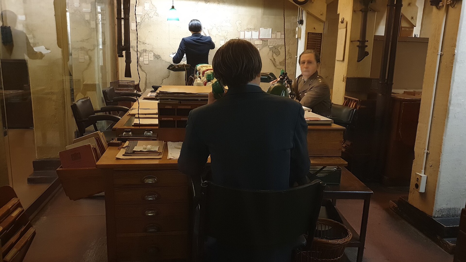 The Map Room of the Churchill War Rooms, with a figure of an officer at a desk of telephones.