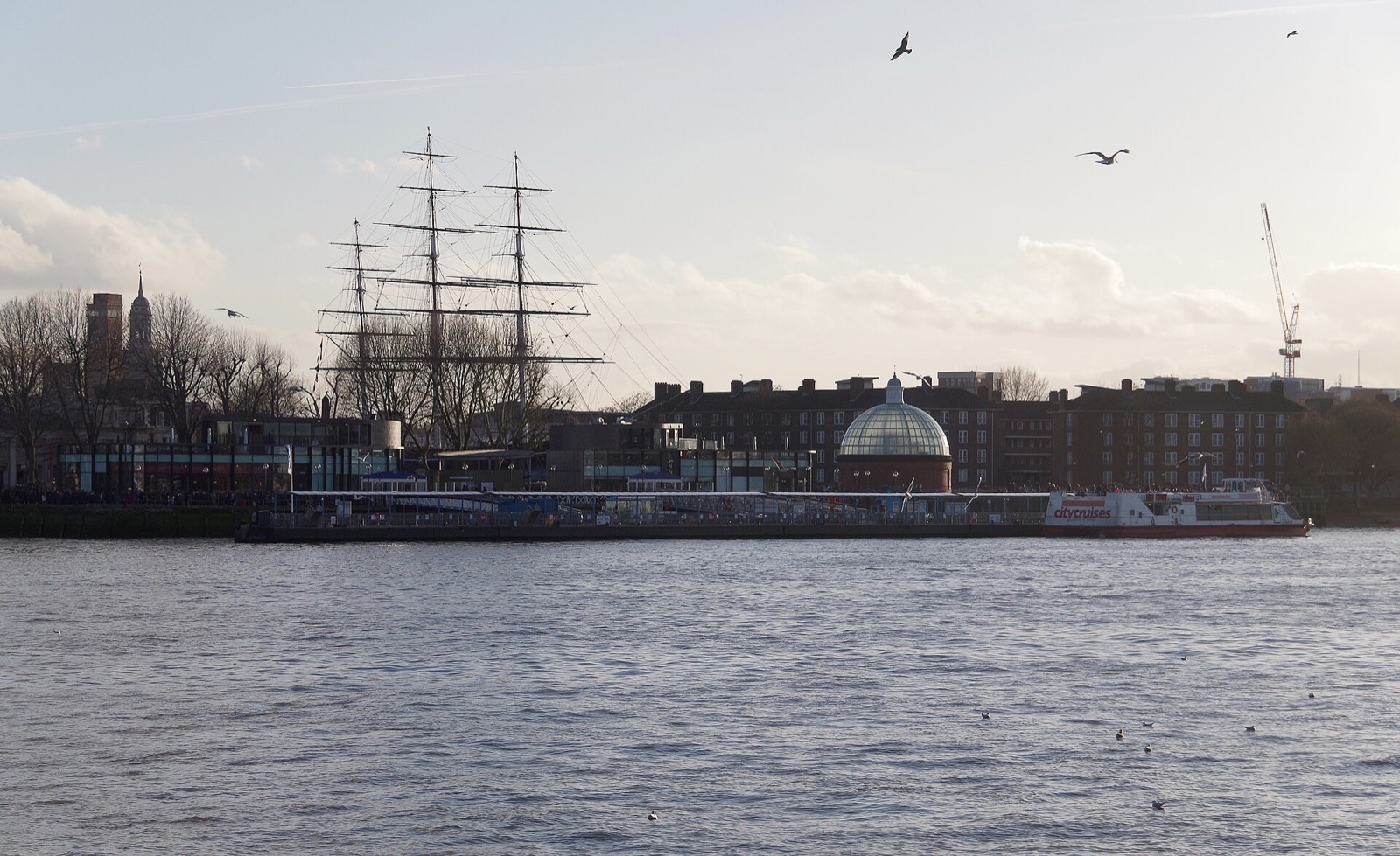 The masts of the Cutty Sark above the riverside at Greenwich, seen across the Thames.