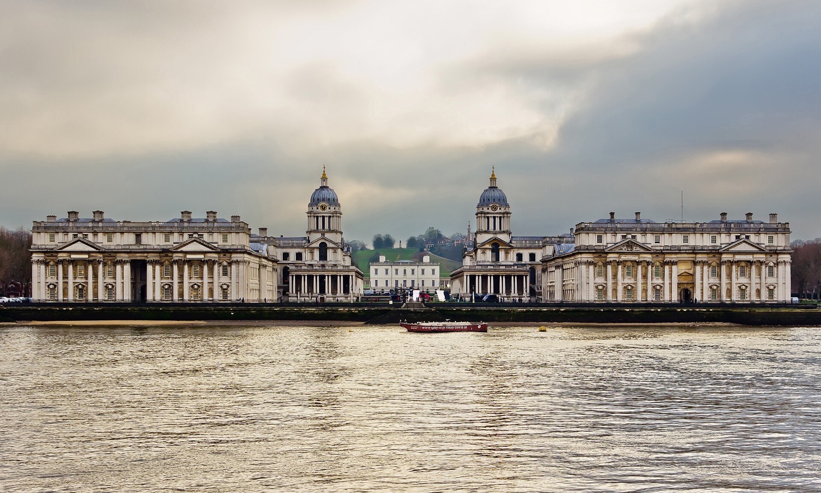 The Old Royal Naval College at Greenwich seen from the Thames, two domed ranges either side of the Queen's House.