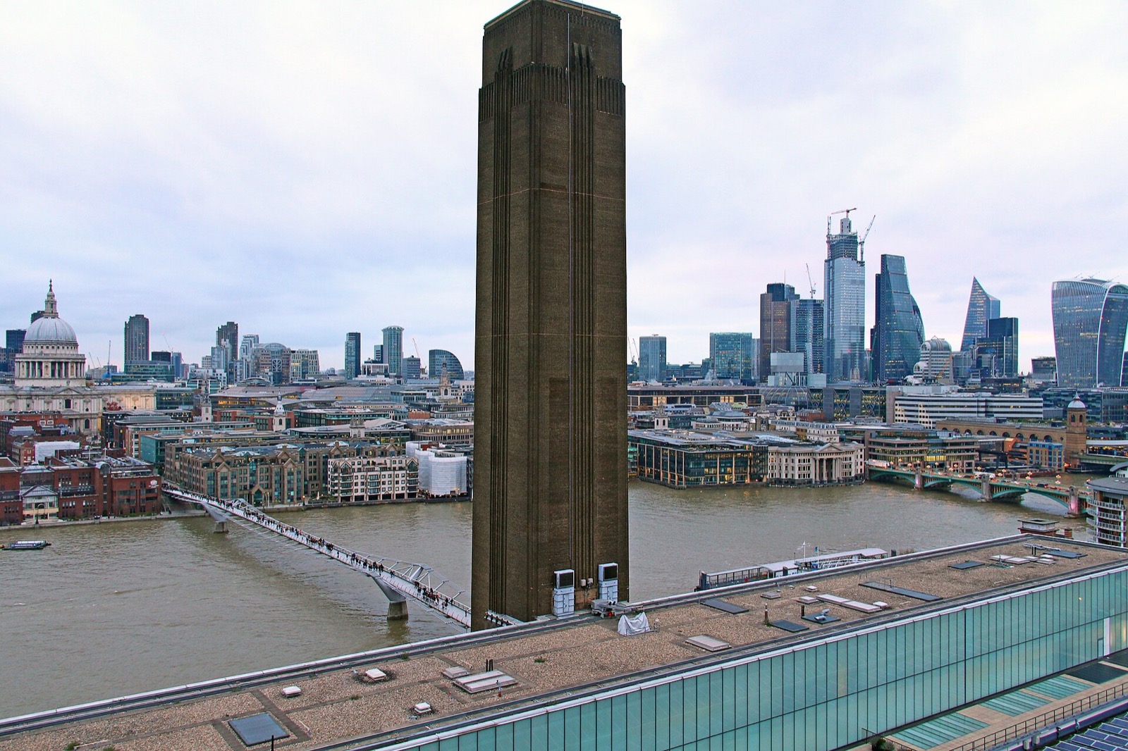Tate Modern and its chimney from above, with the Thames and the towers of the City behind.