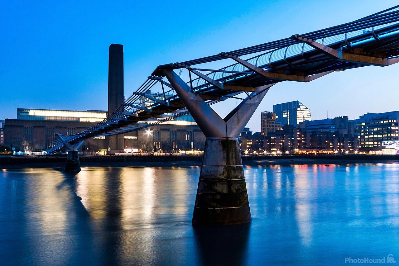 Tate Modern at dusk, its brick chimney rising at the end of the Millennium Bridge.