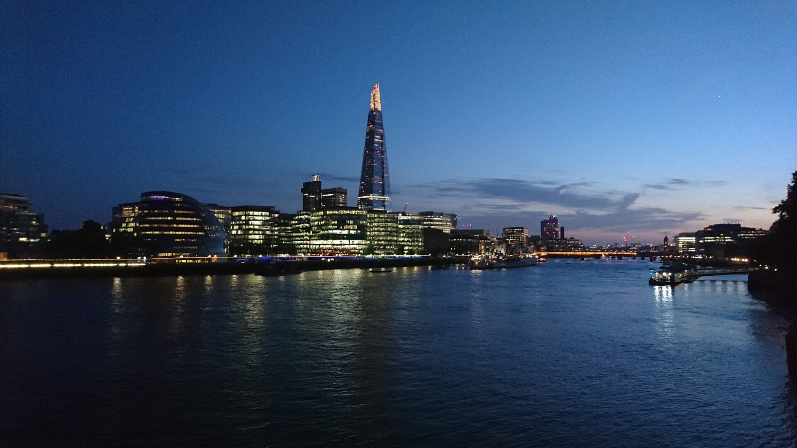 The Shard lit at dusk, seen across the Thames from Tower Bridge.