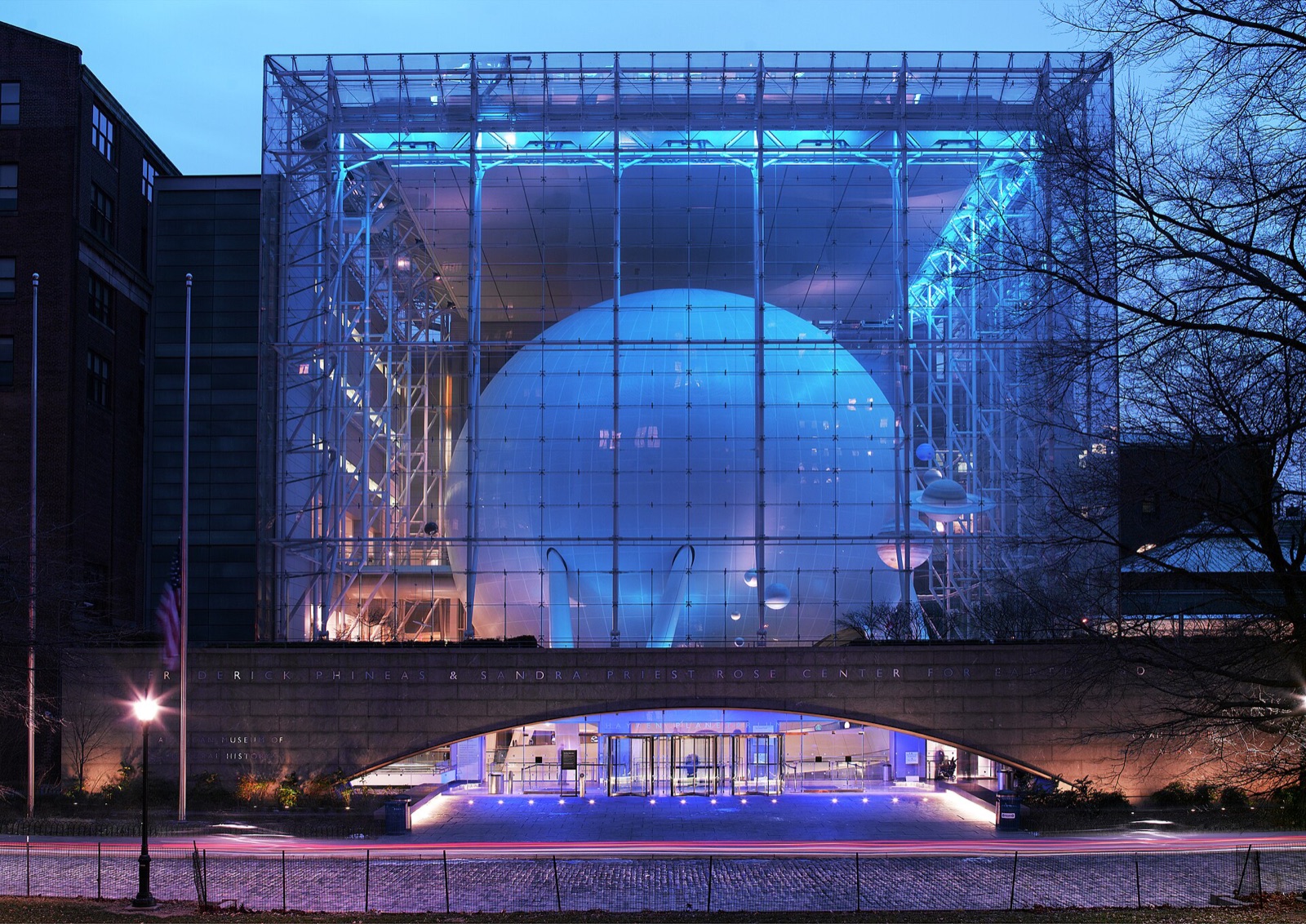 The Rose Center for Earth and Space at dusk, a glass cube lit blue with a great sphere inside it.