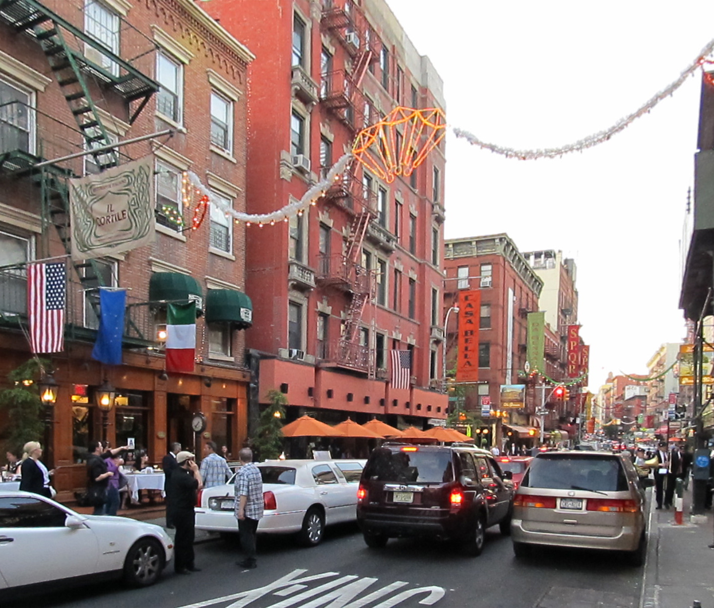 Mulberry Street in Little Italy, with restaurants along the pavement and decorations strung across the street.