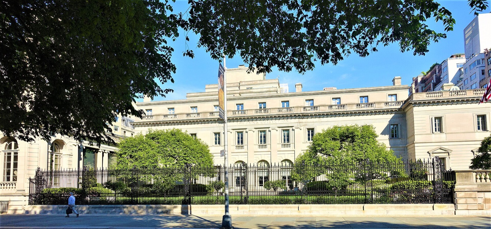 The Frick Collection seen from Fifth Avenue, a long low mansion of pale stone behind a garden and railings.