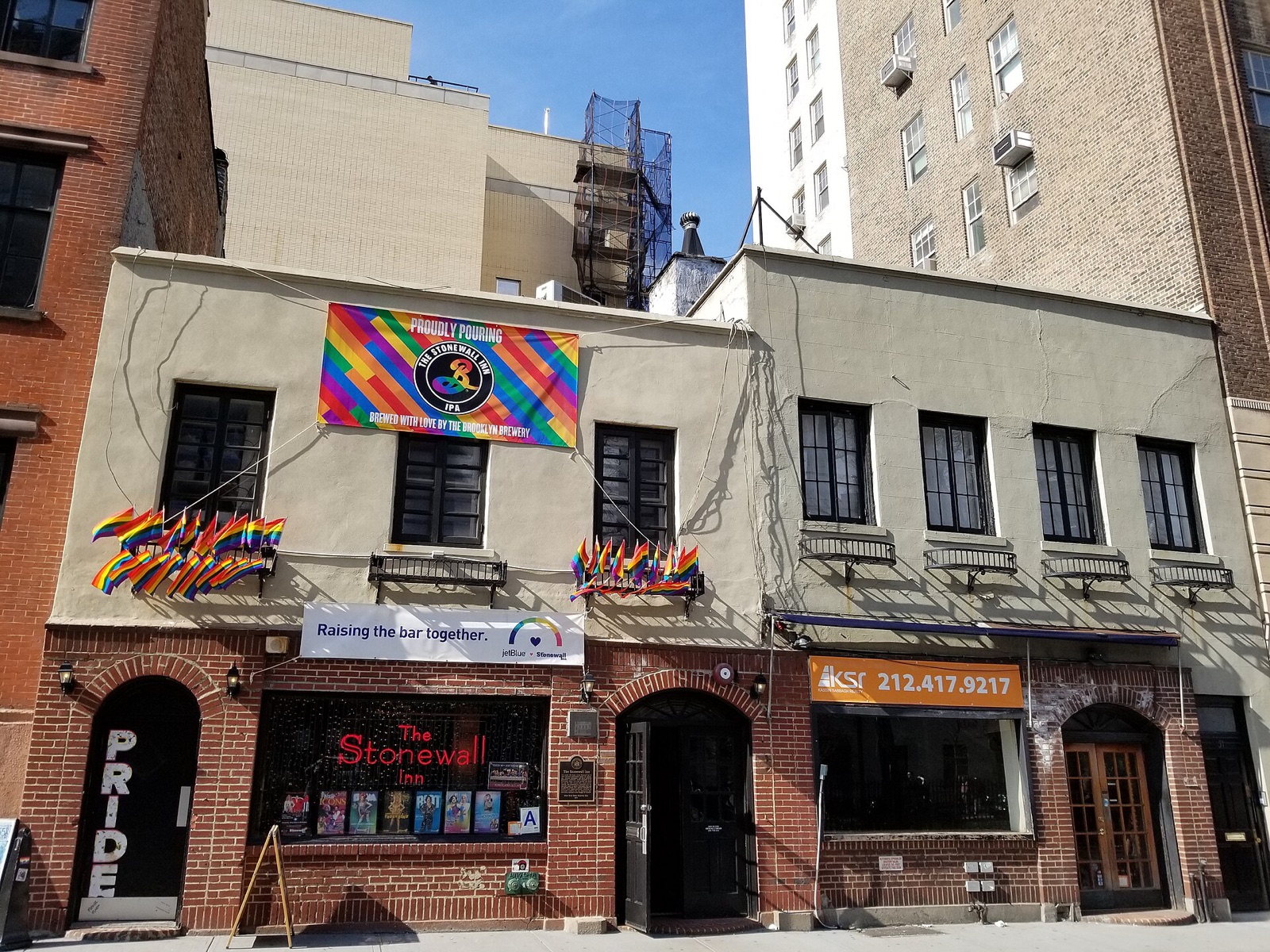The Stonewall Inn on Christopher Street, a low brick building hung with rainbow flags.