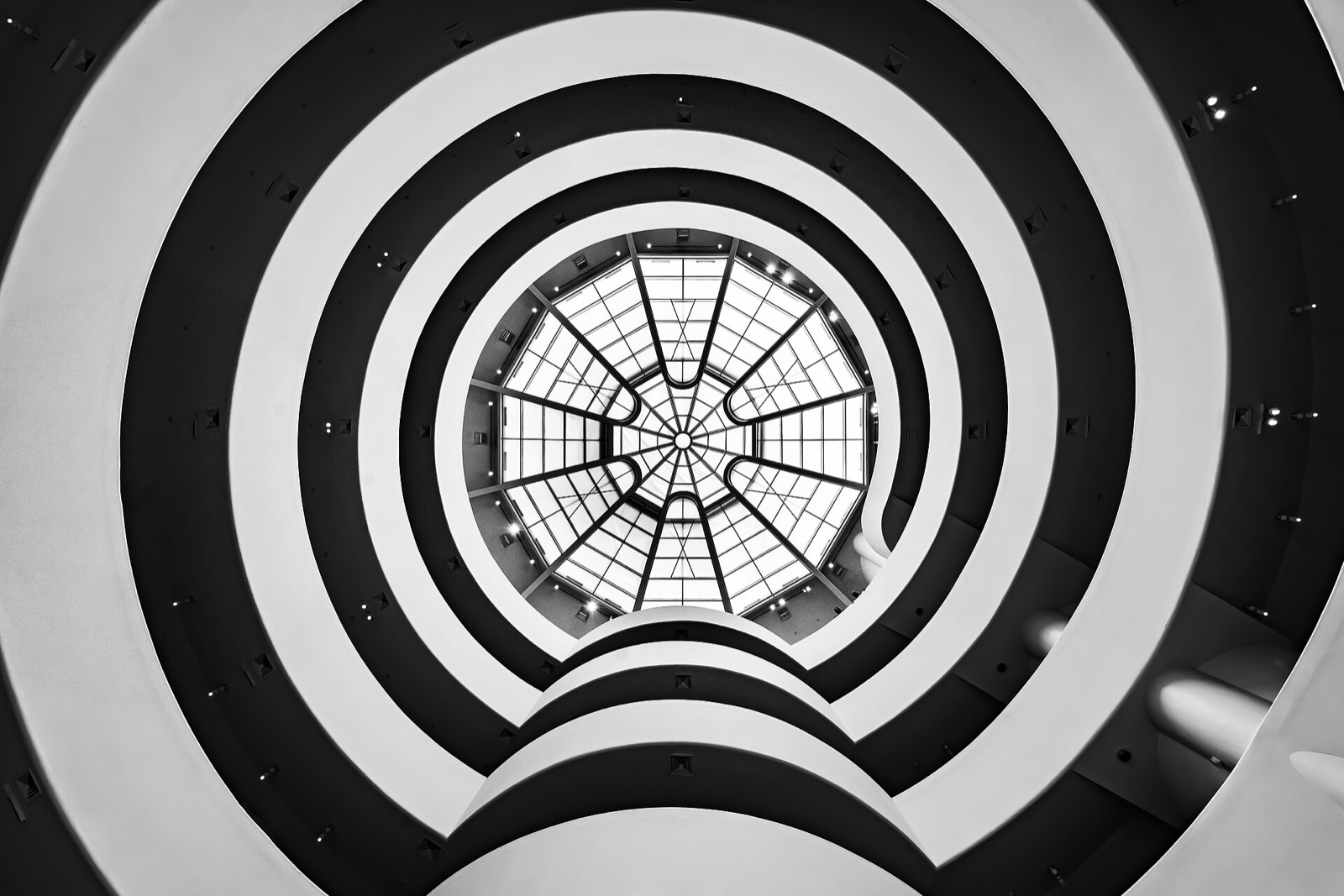 The rotunda of the Guggenheim Museum from below, the white ramps circling up to a glass dome.