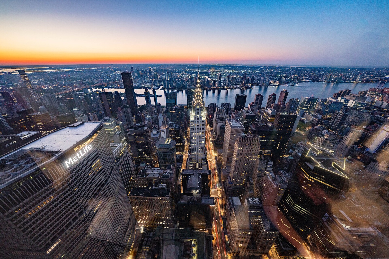 The Chrysler Building at sunrise, seen from SUMMIT One Vanderbilt, with the East River behind it.