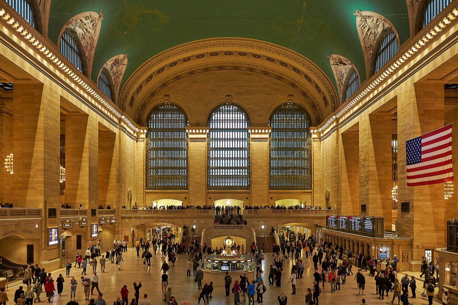 The Main Concourse of Grand Central Terminal, its arched windows and blue-green ceiling above the crowd.
