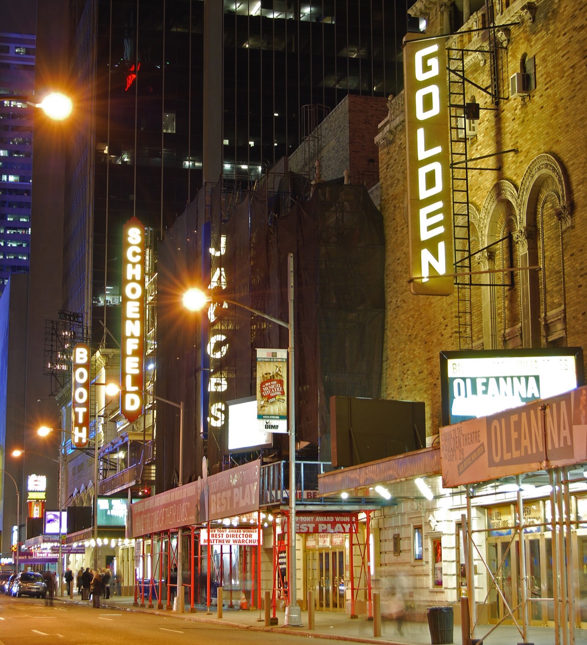 The lit signs of Broadway theatres along West 45th Street at night.