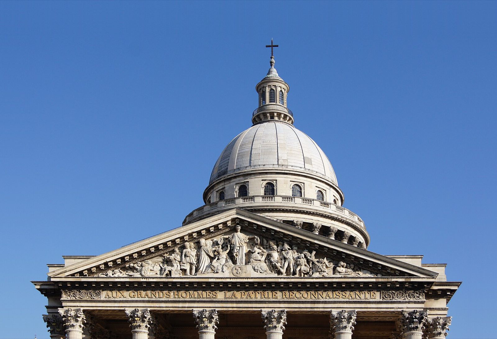 The portico, pediment and dome of the Panthéon in Paris against a blue sky.