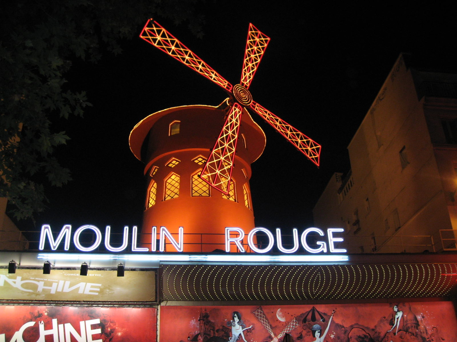 The Moulin Rouge at night, its red windmill and neon sign lit above the boulevard.