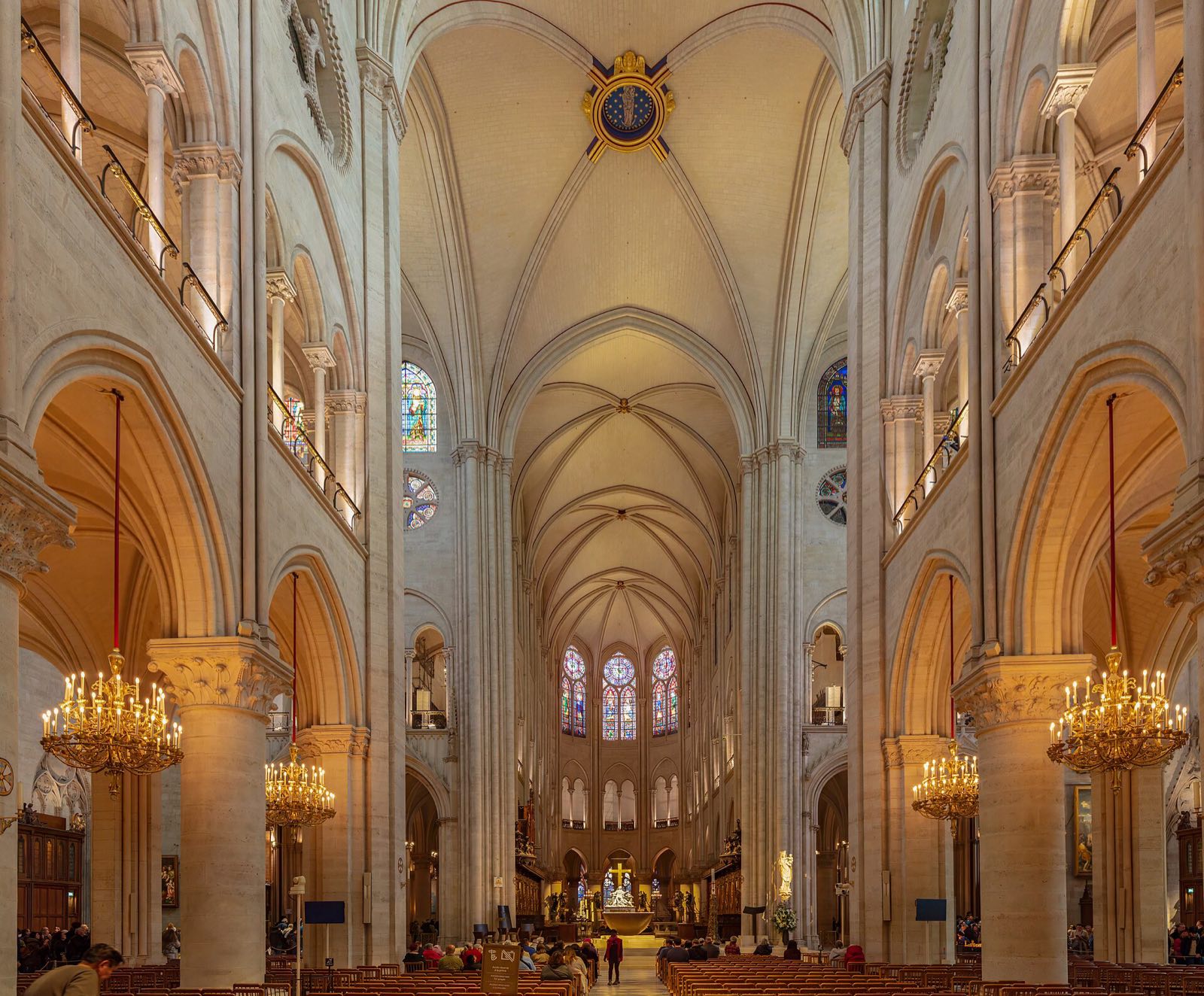 The nave of Notre-Dame after its restoration, pale stone vaults and chandeliers.