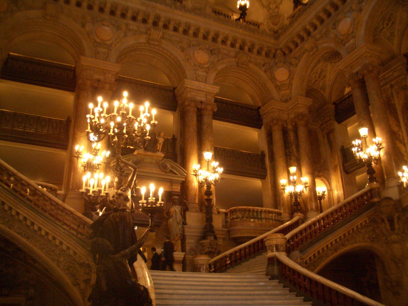 The grand staircase of the Palais Garnier, marble steps under gilded balconies and candelabra.