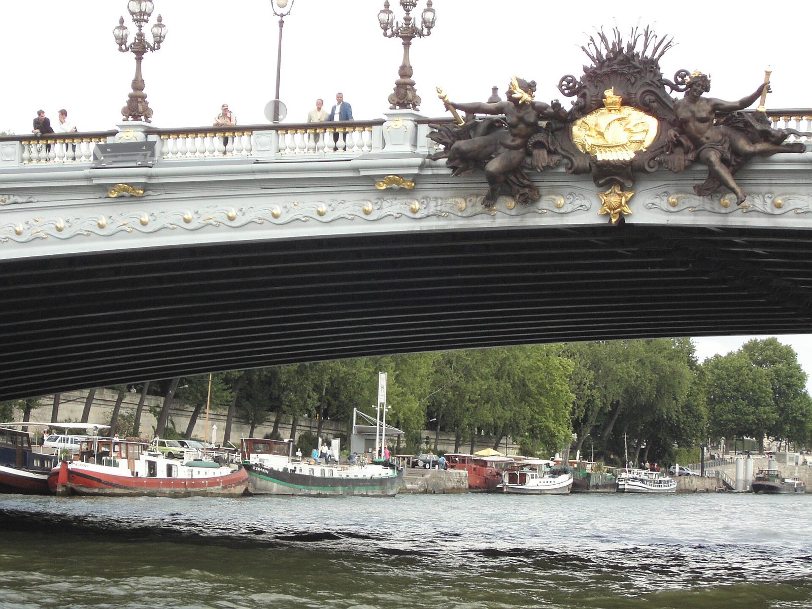 The Pont Alexandre III seen from a boat on the Seine, its lamps and gilded ornament above the arch.