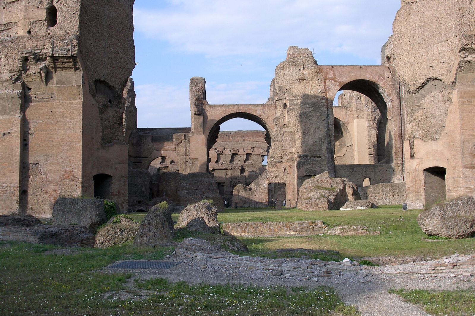 The tall brick walls and arches of the Baths of Caracalla, with pines in front.