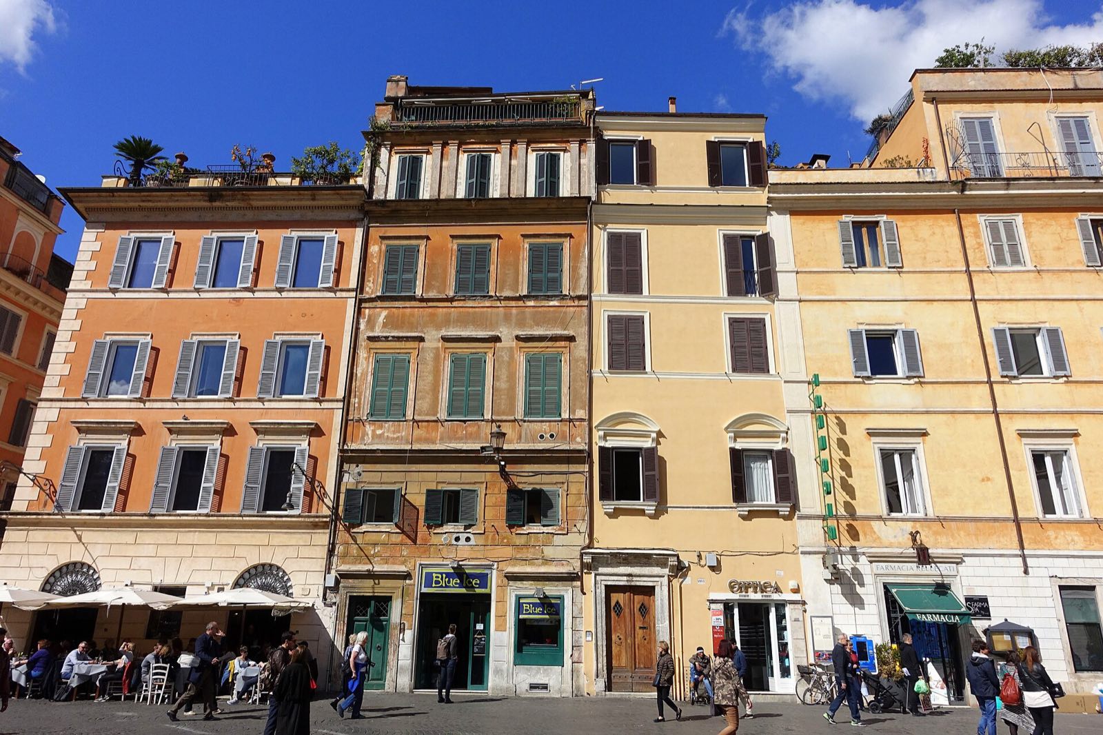 Ochre and pink houses with café tables on the square of Santa Maria in Trastevere.