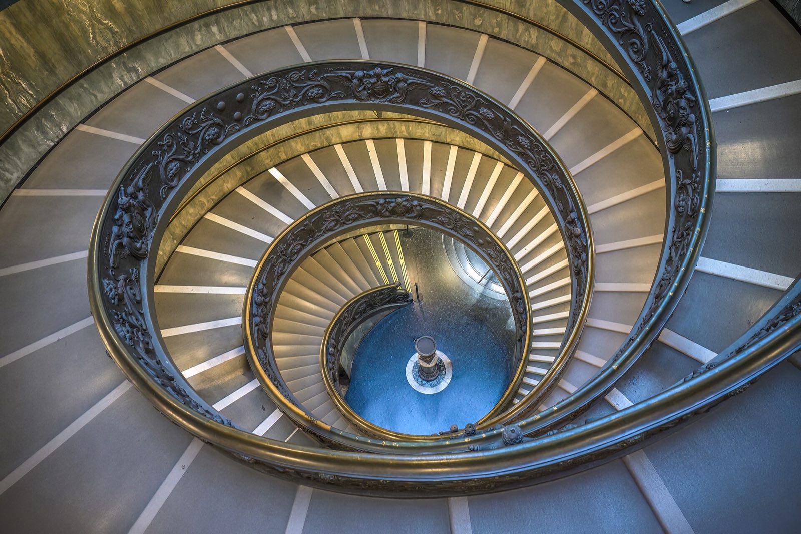 The double spiral staircase of the Vatican Museums seen from above, with visitors walking down it.
