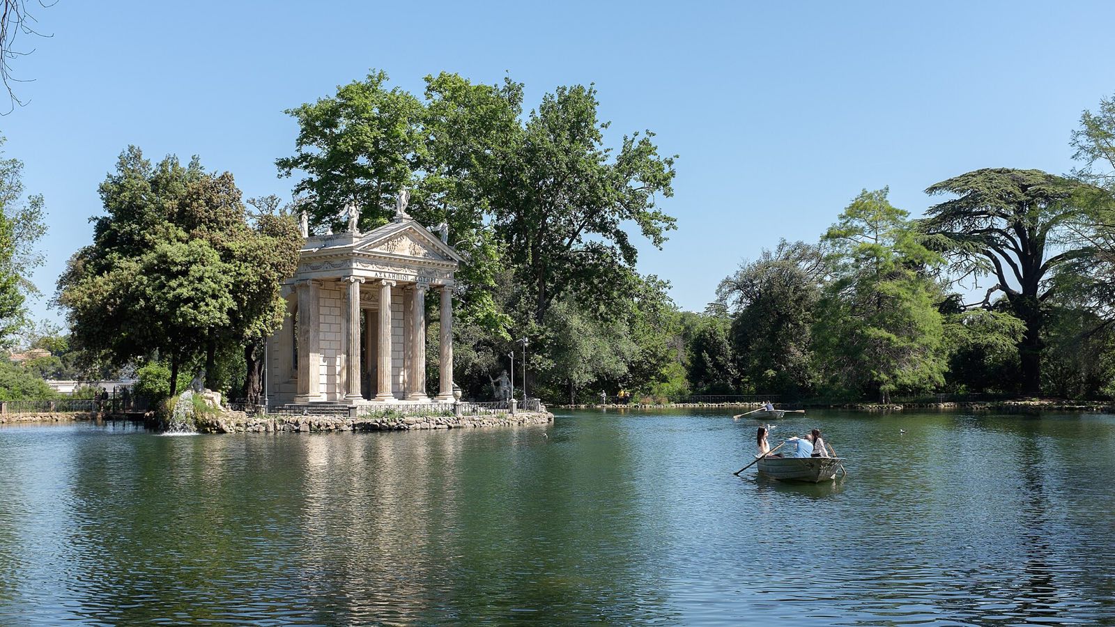 The small temple of Aesculapius on its island in the lake of Villa Borghese, among trees.